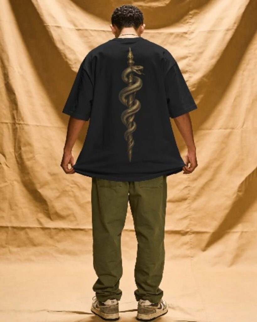 Back view of a man wearing an oversized black streetwear t-shirt with a golden snake wrapped around a dagger graphic